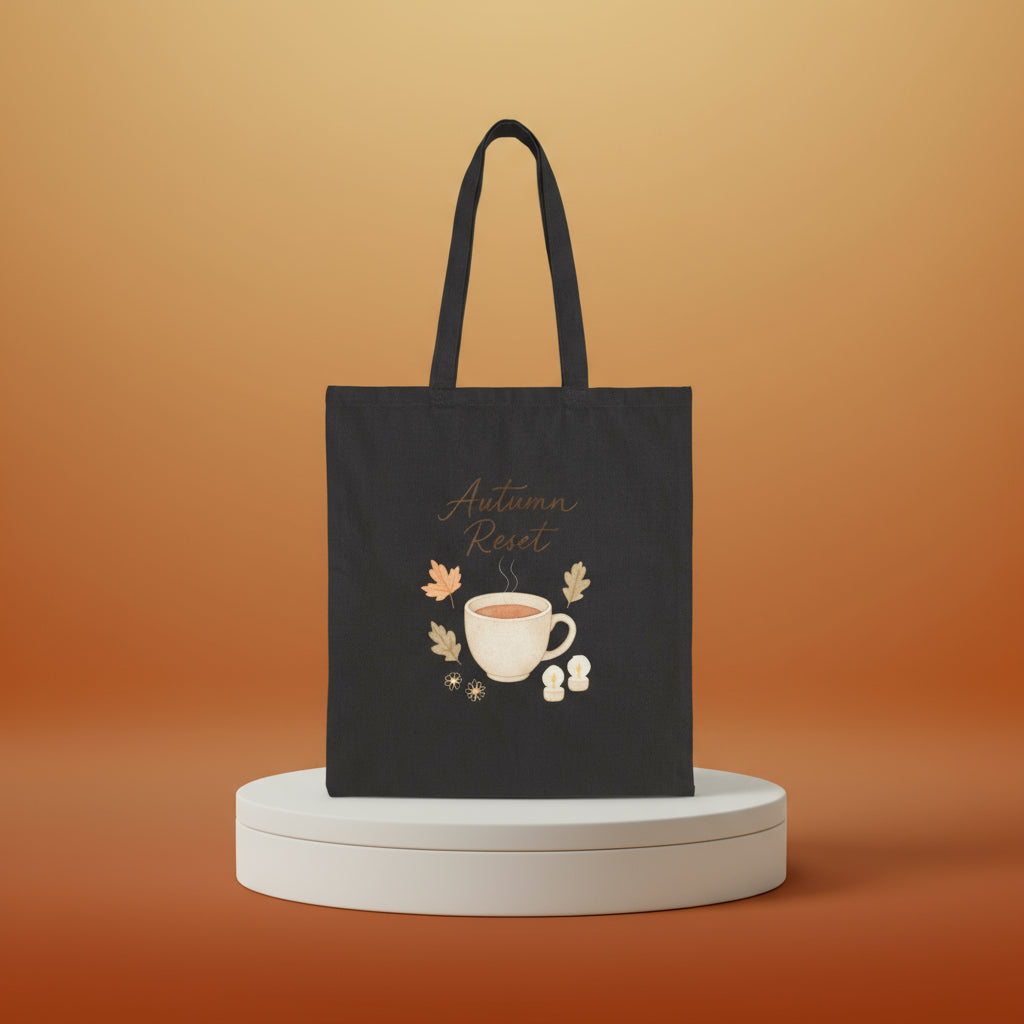 Black tote bag with 'Autumn Reset' design featuring a cup and leaves on a white background